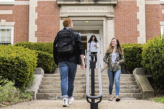 Photo of three Chatham University 学生s walking on Shadyside Campus in front of a red brick building